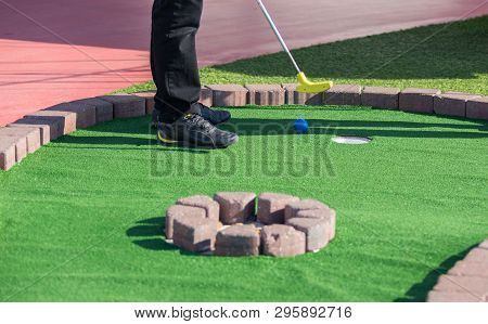 A Man Prepares To Hit A Ball During Mini Golf Game