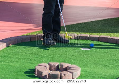 A Man Prepares To Hit A Ball During Mini Golf Game