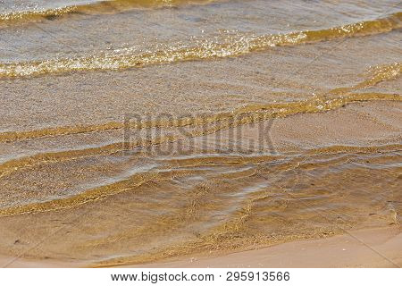 View Of The Sandy Bottom Through The Water With Reflections Of The Sun For Background Or Texture