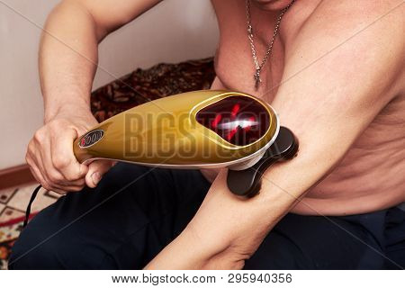 An Old Man With Gray Hair Doing His Own Neck Massage With An Electric Massager At Home. Restoration 