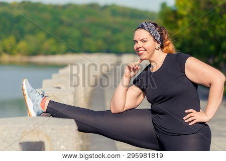 Woman Portrait Plus Size Performs Stretching Exercises On The Embankment In A City Park In The Early