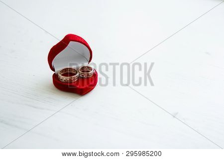The Red Box In The Form Of A Heart Is Open On A White Steel. In It Are Two Wedding Gold Carved Rings