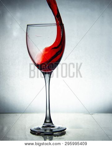 Splash Of The Drink In The Glass On The High Leg On Colored Background