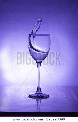Splash Of The Drink In The Glass On The High Leg On Colored Background