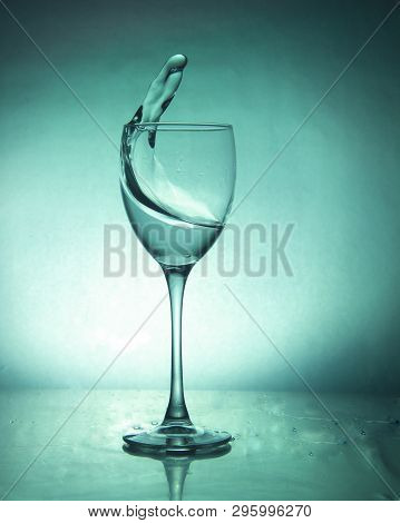 Splash Of The Drink In The Glass On The High Leg On Colored Background