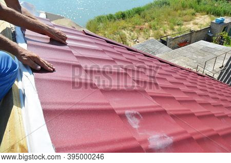 Roofing Construction. A Building Contractor Is Installing Red Metal Corrugated Roof Tiles, Shields A