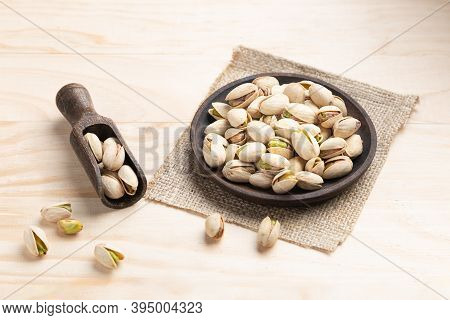 Pistachios On Wooden Spoon And Dish On Light Wooden Base.
