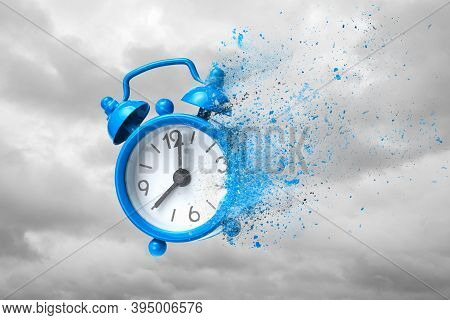 Time Is Running Out. Blue Alarm Clock Waving Like Sand Or Ashes Against Background Of Clouds