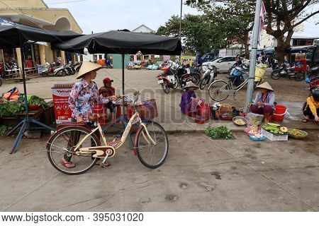 Hoi An, Vietnam, November 16, 2020: A Woman Arrives With Her Bicycle At A Stall In One Of The Street