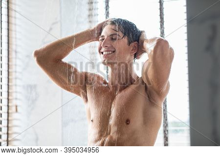 Selfcare And Wellness Concept. Portrait Of Smiling Handsome Young Man Taking A Shower Standing Under