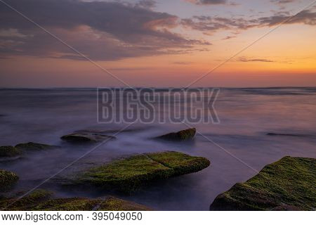 Calm Ocean Long Exposure. Stones Covered By Geen Moss In Mysterious Mist Of The Sea Waves. Concept O