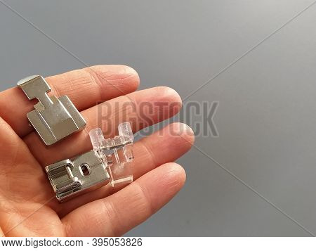 A Set Of Feet For An Electric Sewing Machine In A Female Hand. Gray Backdrop. Standard Sewing Or Zig