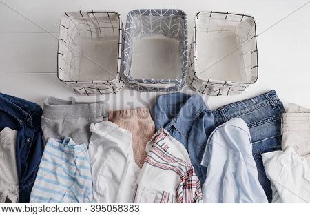 A Group Of Organic Cotton Clothing Set On A White Table Is Ready To Be Folded Into White Baskets.the