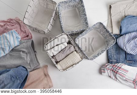 A Group Of Organic Cotton Clothing Set On A White Table Is Ready To Be Folded Into White Baskets.the