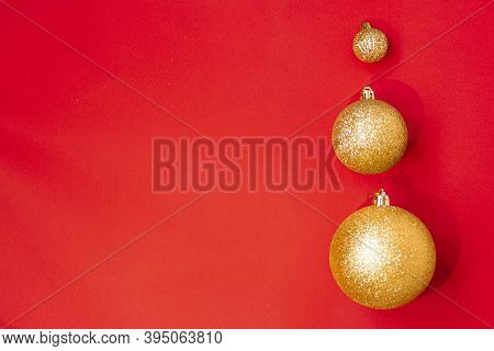 Three Golden Christmas Balls Of Different Sizes Are Displayed In A Row As A Border On A Red Backgrou