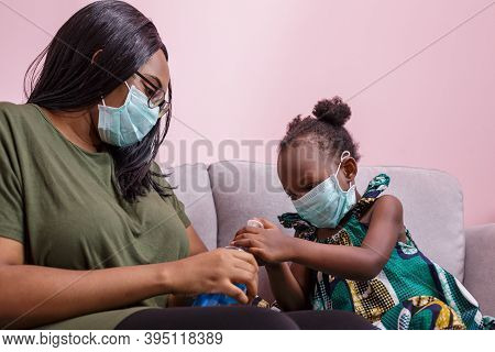 African Americans' Mother And Daughter Wearing A Mask Are Washing Their Hands With Alcohol To Protec