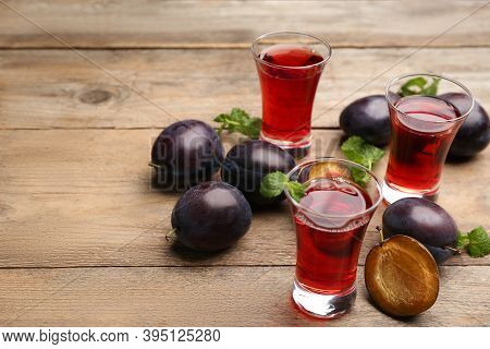Delicious Plum Liquor, Mint And Ripe Fruits On Wooden Table. Homemade Strong Alcoholic Beverage