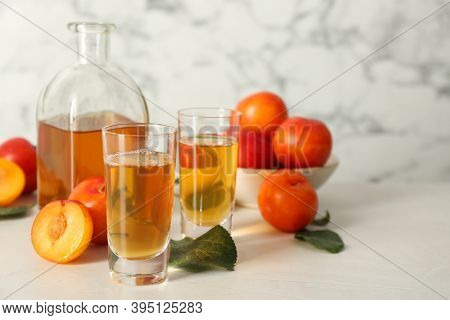 Delicious Plum Liquor And Ripe Fruits On White Table. Homemade Strong Alcoholic Beverage