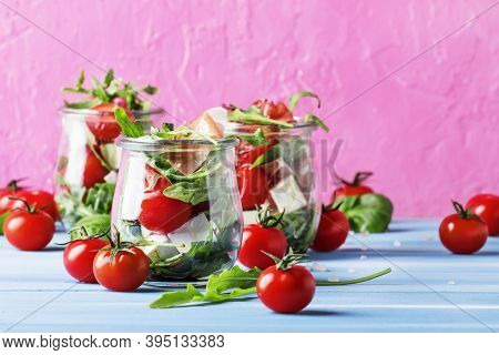 Summer Salad With Arugula, Soft Cheese, Cherry Tomatoes And Prosciutto In Glass Jars, Festive Backgr