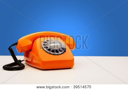 Telefone vintage de laranja em fundo azul