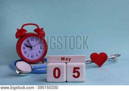 5st May. White Wooden Calendar Blocks With Date, Clock And Stethoscope On A Blue Pastel Background. 
