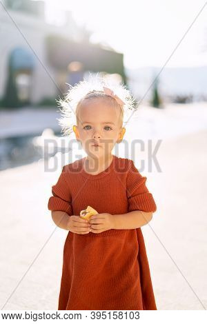 A Sweet Little Girl Is Holding An Apple Pirogi By The Fountain In The Park