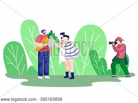 Photographer Holds A Photo Session With Clients In The Park. Couple In Love Is Photographed By The P