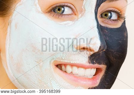 Woman With Clay Carbo Black Mask On Half Face And White Mud On Second Half. Girl Taking Care Of Oily