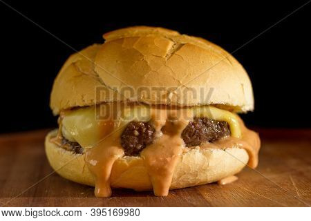 Close Up Of A Homemade Classic Burger On A Chopping Wood Board, On Black Background