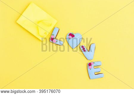 Inscription Love By Homemade Cookies With Blue Icing On Yellow Pastel Color. Cakes Escaped From Pape