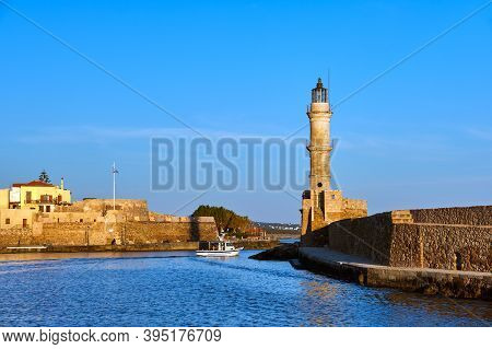 Fishing Boat Pass By Famous Lighthouse And Walls Of Old Port, Firka Fortress, Old Venetian Harbour O