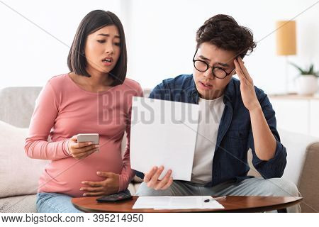 Family Struggling Financial Crisis. Depressed Japanese Couple Looking At Invoice Bills Not Able To P