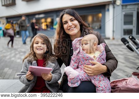Happy Mother Smiling And Sitting Alongside Her Happy Daughters