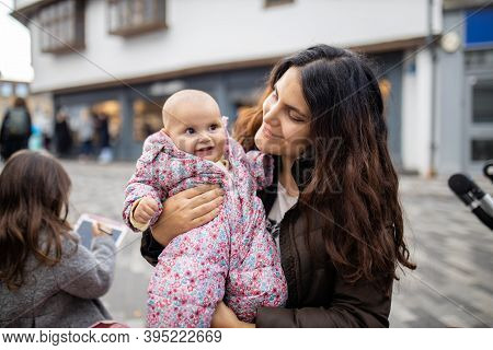 Happy Beautiful Mother Smiling And Holding Her Baby Daughter