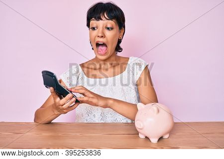 Beautiful brunettte woman caculating money savings celebrating crazy and amazed for success with open eyes screaming excited. 