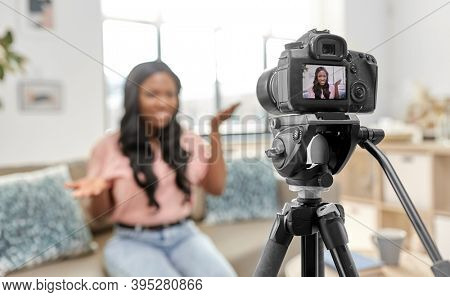 blogging, videoblog and people concept - happy smiling african american female video blogger with camera videoblogging at home