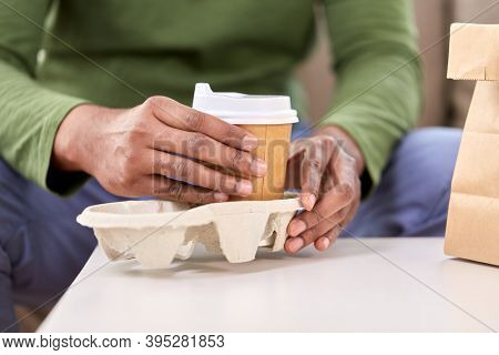 consumption and people concept - close up of man with takeaway coffee and food at home