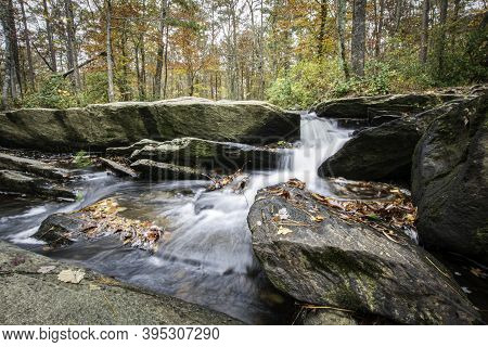 Low Angle View Of The Top Of Cheaha Falls With Colorful Autumn Foliage In The Background.