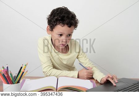 Boy With Book At A Table After Going Back To School On White Background Stock Photo