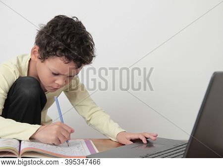 Boy With Book At A Table After Going Back To School On White Background Stock Photo