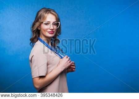Medical Concept Of European Beautiful Female Doctor In Surgical Suit With Stethoscope, Waist Up. Med