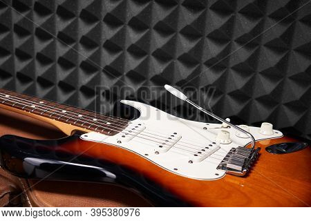 Sunburst Electric Guitar Lying On Acoustic Foam Panel Background