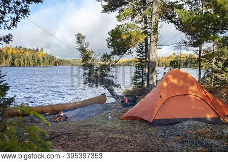 Campsite With Orange Tent On Northern Minnesota Lake At Sunrise During Autumn
