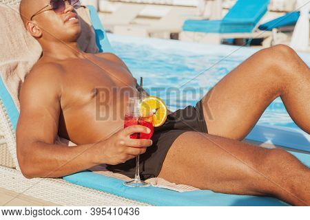 Cropped Shot Of A Muscular African Man Relaxing Near The Swimming Pool, Holding Cocktail, Copy Space