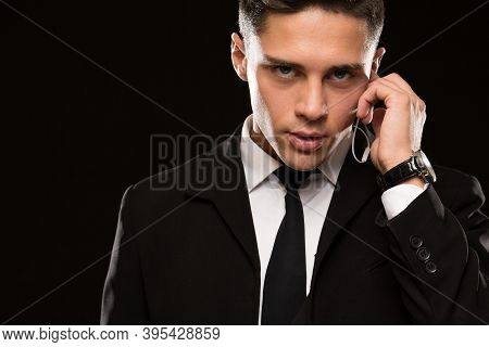 Close Up Of A Handsome Young Suited Secret Service Agent Looking To The Camera Fiercely Talking On H