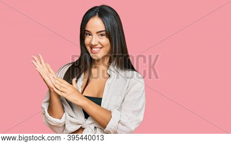 Young beautiful hispanic girl wearing casual clothes clapping and applauding happy and joyful, smiling proud hands together 
