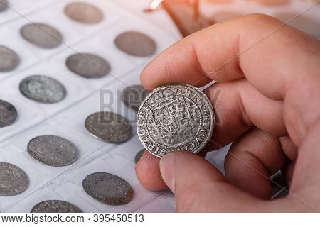 Numismatics. Old Collectible Coins Made Of Silver On A Wooden Table. A Collector Holds An Old Coin.