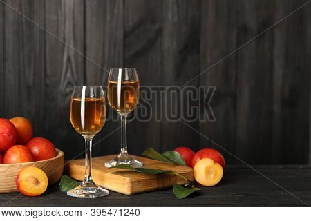 Delicious Plum Liquor And Ripe Fruits On Black Wooden Table. Homemade Strong Alcoholic Beverage