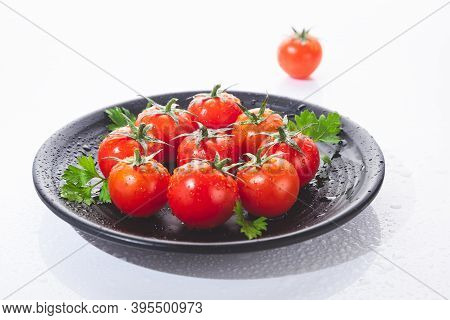 Fresh Cherry Tomatoes On Black Round Plate, Isolated On White Background.