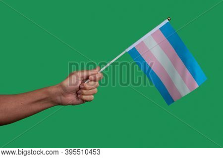 closeup of a young caucasian person waving a transgender pride flag on a green background